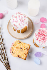 Easter cake with raisins in sugar glaze. festive pastries with pink sprinkles, painted eggs, pussy willow and Easter decor on a white background. religious holiday 