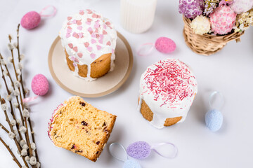 Easter cake with raisins in sugar glaze. festive pastries with pink sprinkles, painted eggs, pussy willow and Easter decor on a white background. religious holiday 
