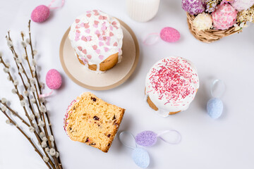 Easter cake with raisins in sugar glaze. festive pastries with pink sprinkles, painted eggs, pussy willow and Easter decor on a white background. religious holiday 