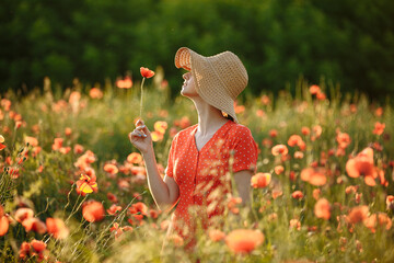 girl with a big hat in a field of red poppies
