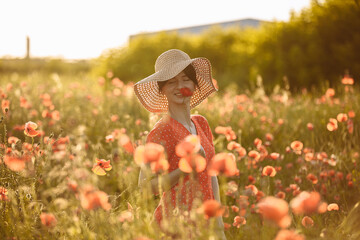 girl with a big hat in a field of red poppies