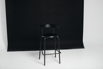 A stylish black chair stands on a black background in the studio room. The concept of a vacancy or an interview. Cinema, director's chair.