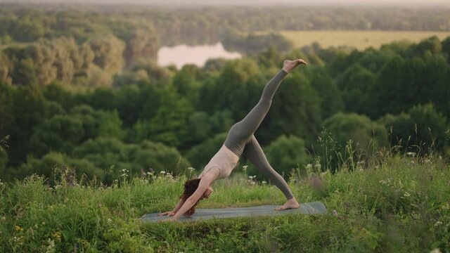 Pretty girl doing yoga and pilates in the mountain forest. Fitness girl training outdoors in landscape of nature.