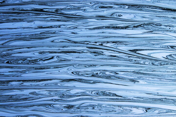 Abstract background with the effect of iridescent paint. Black and blue paint stains