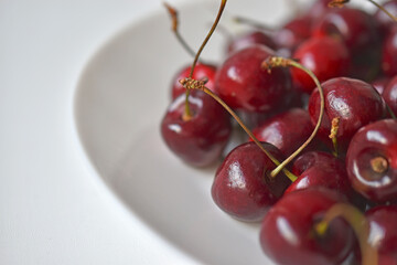 Red and ripe cherries on a white plate