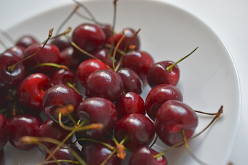 Red and ripe cherries on a white plate