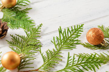 fir branches, thuja twigs, golden Christmas balls, fir cones on a white wooden