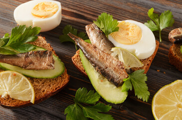  sandwiches with bread, sprats, fresh cucumber, boiled eggs and parsley,