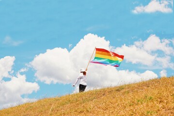 Woman holding rainbow flag and running on the mountain.