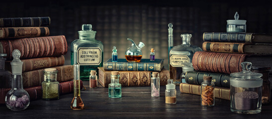 Glass bottles, old books on table of a scientist. Medicine, chemistry, pharmacy, apothecary,...