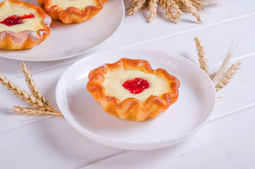 Fresh tasty tartlet with filling on white plate on wooden background