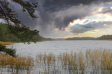 Fototapeta premium Dramatic sunset by the lake in autumn before a thunderstorm.