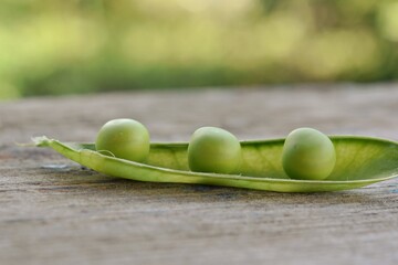vegetables peas open pod with ripe peas on a blurred background on a wooden surface