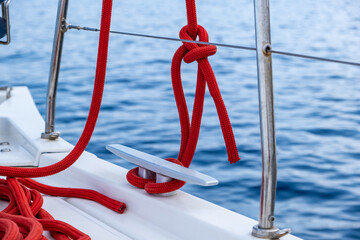 Sailing boat mooring rope tied on cleat, blur sea water background