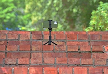 iPhone on a tripod on a brick staircase on a green background