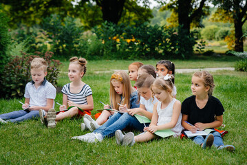 Fototapeta premium A teacher teaches a class of children in an outdoor Park. Back to school, learning during the pandemic