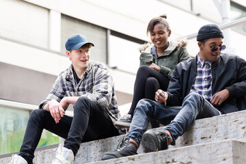Group of young friends sitting on staircase making fun