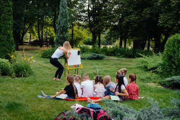 A teacher teaches a class of children in an outdoor Park. Back to school, learning during the pandemic