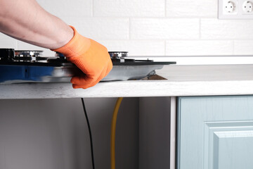 Serviceman installs  new gas hob in  kitchen countertop