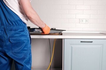 Serviceman installs  new gas hob in  kitchen countertop