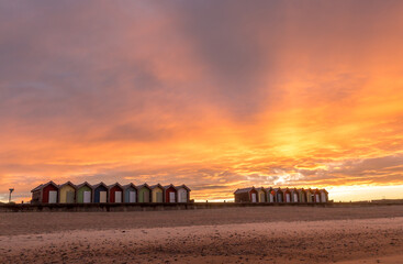 Fototapeta premium The vibrant and colorful beach huts by the promenade overlooking Blyth beach with a lovely sunset in Northumberland, England