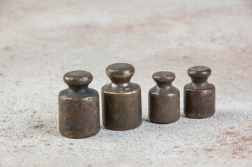Four antique bronze weights for scales on concrete background.