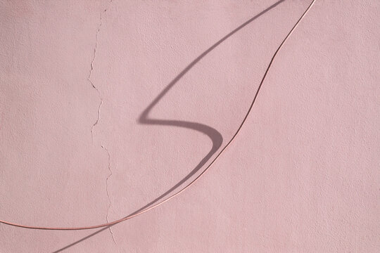 wire and shadow from it against the background of a wall with a crack