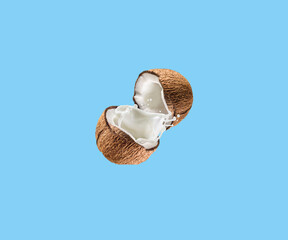 Coconut on a blue background. The two halves of the coconut are in the center of the image. Healthy fruit