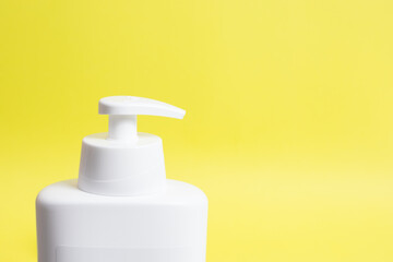 Fototapeta na wymiar White unbranded dispenser bottle isolated on yellow background. Moisturising Lotion. Sunscreen.