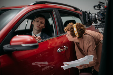 Professional male actor works in the frame on the set. Shooting with a car on a large white...