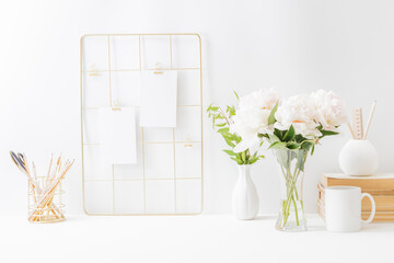 Home office desktop and mood board with empty card, white peonies in a vase, office supplies on a light background