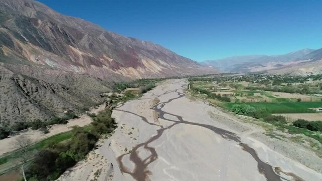 Sobrevolando un rio seco en jujuy argentina, con cultivos en sus laderas y bellos cerros de colores, tipicos de la region.