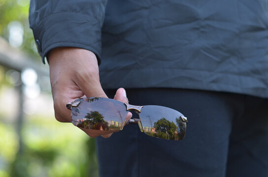 man hand holding Black Glasses or sun glasses with vintage style and blurred background