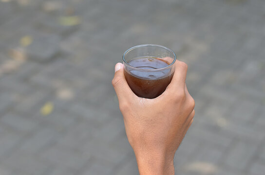 male hand holding Iced Coffee in the glass refreshing look with blurred background. selective focus