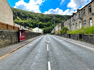 Looking down, Burnley Road, with Victorian terrace houses, hills, and trees in Cornholme, UK