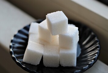 closeup sugar cubes in a black bowl