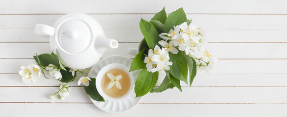 Jasmine flowers and teapot on white wooden background. Herbal tea of jasmine flower. Flat lay.
