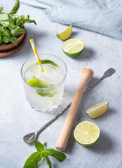 glass of lime lemonade mojito on the table with lime slices, juicer, spoon and mint . Top view