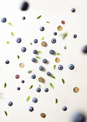 Concept flat lay with a  few juicy blueberries levitation with green leaves on yellow background. Top  view and close up