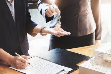 Real estate agents agree to buy a home and give keys to clients at their agency's offices. Concept...
