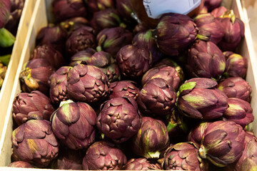 Obraz premium Venta de alcachofas moradas en mercado.