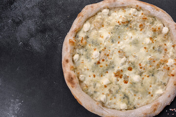 Fresh delicious Italian pizza with four kinds of cheese on a dark concrete background
