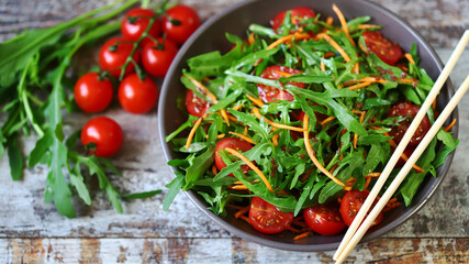 Selective focus. Healthy salad bowl with arugula, carrots and cherry tomatoes.