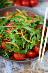 Selective focus. Healthy salad bowl with arugula, carrots and cherry tomatoes.