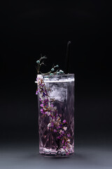 luxury violet fizz cocktail drink with flower decoration on black background