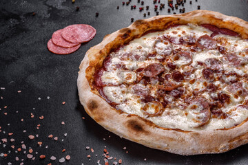 Fresh delicious Italian pizza with four types of meat on a dark concrete background