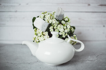 Obraz na płótnie Canvas teapot and cup of tea on a gray background. Vintage white porcelain teapot and cup on a gray board 
