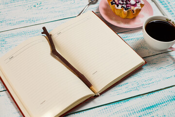 Notepad, a cup of coffee and a cake basket with berries and cottage cheese on a vintage blue and white color. Morning breakfast background. Flatley coffee break layout.