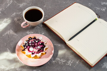 Notepad, a cup of coffee and a cake basket with berries and cottage cheese on a concrete table. Flatley coffee break layout.