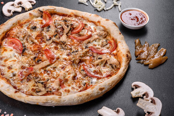 Fresh delicious Italian pizza with mushrooms and tomatoes on a dark concrete background